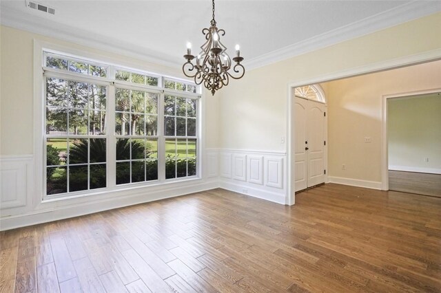 unfurnished dining area with wood-type flooring, an inviting chandelier, and ornamental molding