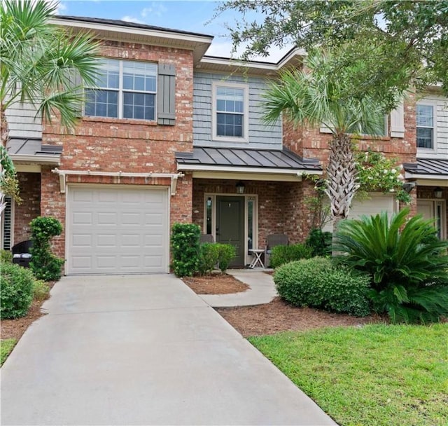 townhome / multi-family property featuring a garage, a standing seam roof, metal roof, and brick siding