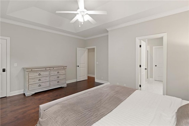 bedroom featuring a raised ceiling, dark wood-type flooring, ornamental molding, a ceiling fan, and baseboards