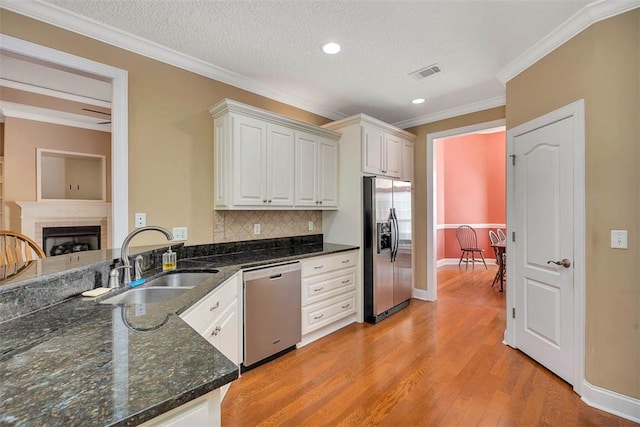 253 Winding Trl, Brunswick, GA 31523 - kitchen with stainless steel appliances, crown molding, tasteful backsplash, light wood-style flooring, and a brick fireplace