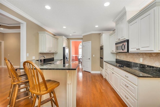 253 Winding Trl, Brunswick, GA 31523 - kitchen with appliances with stainless steel finishes, a breakfast bar area, recessed lighting, a peninsula, and light wood-type flooring