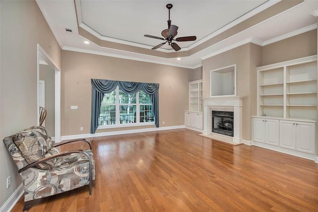 253 Winding Trl, Brunswick, GA 31523 - unfurnished living room with ceiling fan, wood finished floors, a raised ceiling, crown molding, and a fireplace with flush hearth