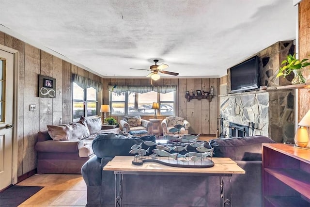 tiled living room with ceiling fan, plenty of natural light, and wooden walls