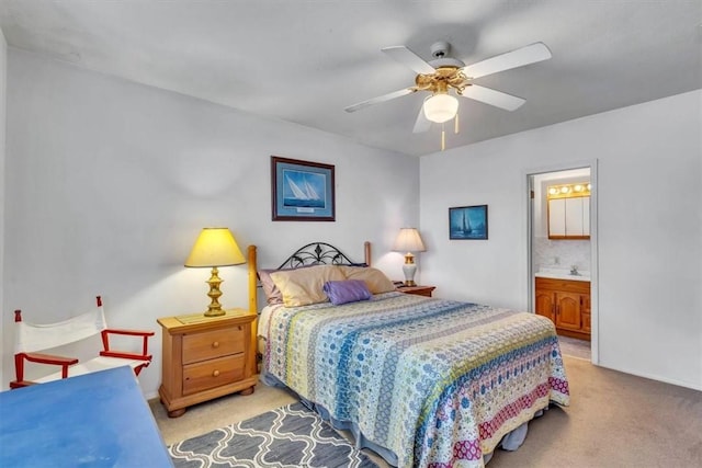 bedroom with ensuite bathroom, ceiling fan, and light colored carpet