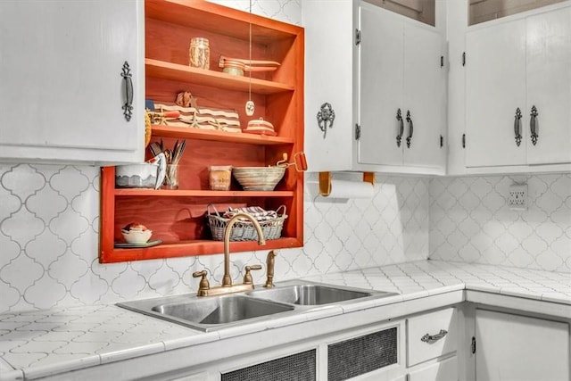 kitchen featuring decorative backsplash, sink, and white cabinets