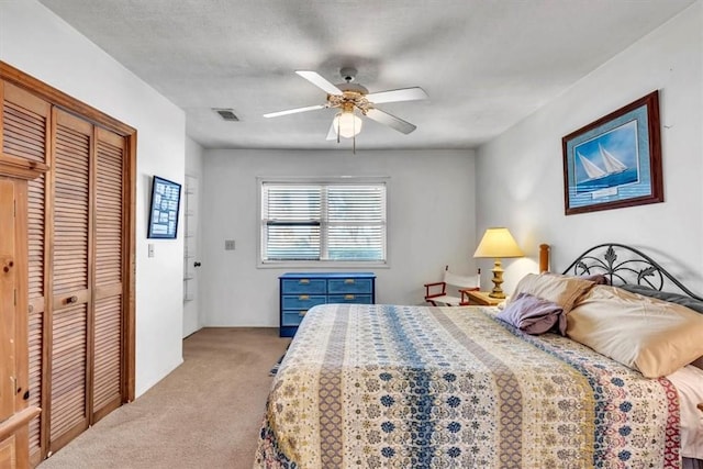 carpeted bedroom with ceiling fan, a textured ceiling, and a closet