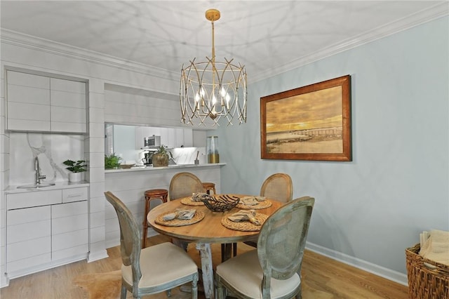 dining area with a chandelier, light wood-style flooring, crown molding, and baseboards