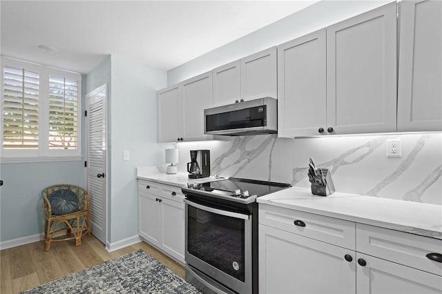 kitchen featuring stainless steel appliances, light wood finished floors, baseboards, and white cabinets