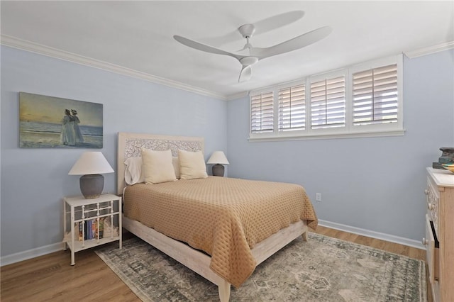 bedroom featuring wood finished floors, crown molding, baseboards, and a ceiling fan