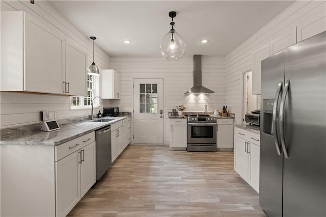 kitchen with white cabinets, decorative light fixtures, wall chimney range hood, and stainless steel appliances