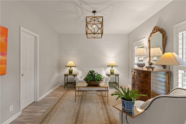 sitting room featuring a chandelier, hardwood / wood-style flooring, and wooden walls