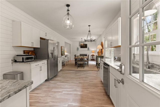 kitchen with appliances with stainless steel finishes, light hardwood / wood-style flooring, white cabinetry, and pendant lighting