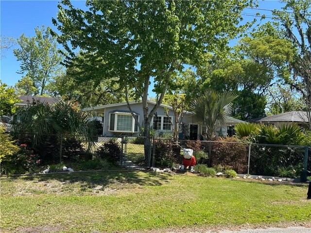 view of property hidden behind natural elements with fence private yard and a front yard