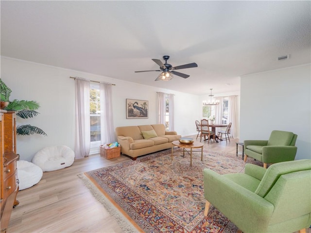 living room with ceiling fan with notable chandelier and light wood-type flooring