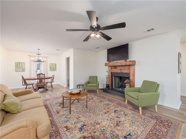 living room with crown molding, ceiling fan with notable chandelier, and light hardwood / wood-style floors