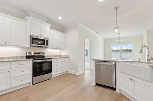 177 Verano St, Kingsland, GA 31548 - kitchen featuring appliances with stainless steel finishes, light wood finished floors, crown molding, a chandelier, and white cabinetry