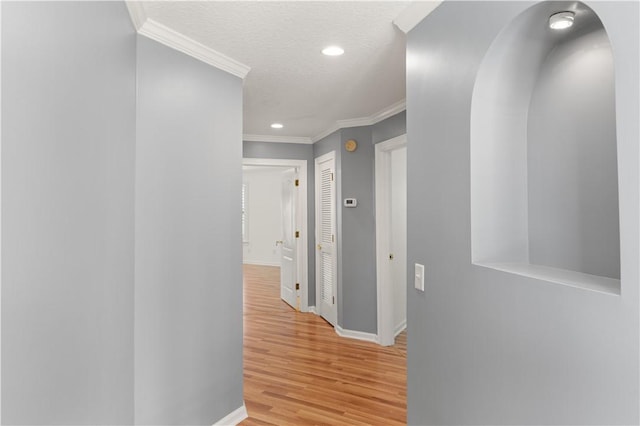 hall featuring light hardwood / wood-style floors, a textured ceiling, and ornamental molding