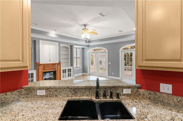 kitchen featuring ceiling fan, sink, a textured ceiling, and ornamental molding