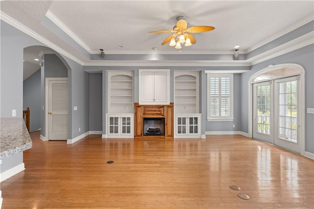 unfurnished living room featuring a textured ceiling, ceiling fan, light wood-type flooring, and crown molding