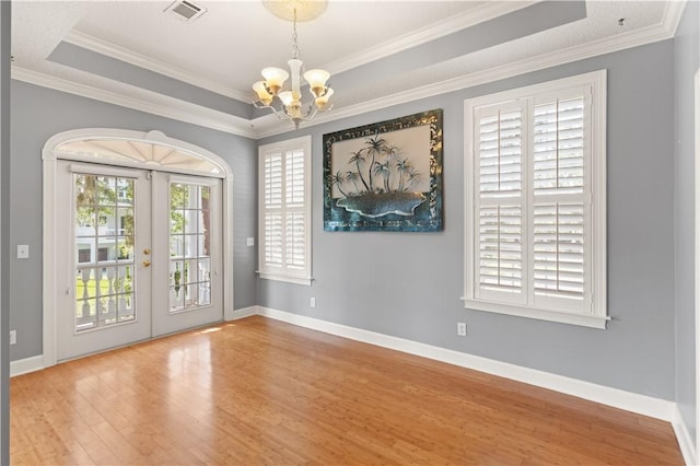 doorway featuring french doors, crown molding, a chandelier, a tray ceiling, and hardwood / wood-style flooring