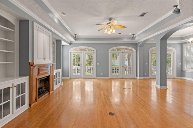 unfurnished living room with french doors, a healthy amount of sunlight, a textured ceiling, and light wood-type flooring