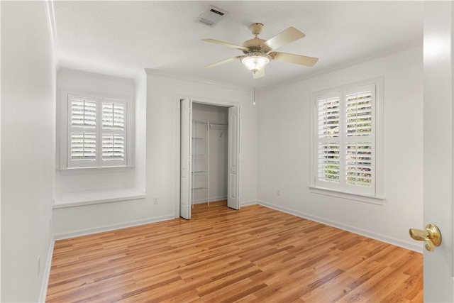 unfurnished bedroom with ceiling fan, a closet, ornamental molding, and light wood-type flooring