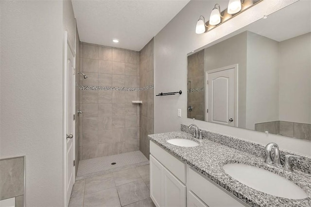 bathroom featuring tile patterned flooring, vanity, and a tile shower