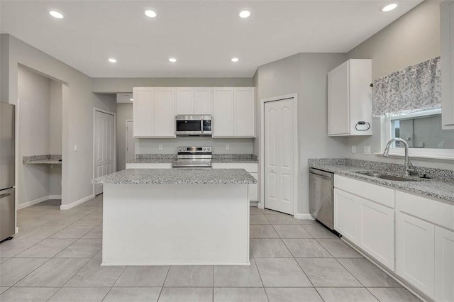 kitchen with stainless steel appliances, white cabinetry, a kitchen island, and sink