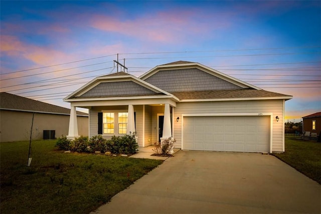 craftsman-style house featuring a garage, central AC unit, and a lawn