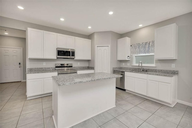 kitchen featuring sink, stainless steel appliances, a center island, and white cabinets