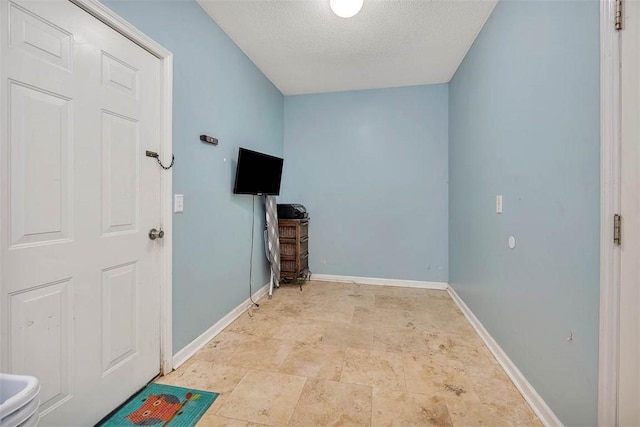 1201 Fairway Rd, Brunswick, GA 31525 - unfurnished living room featuring a textured ceiling, baseboards, and light stone finish floors