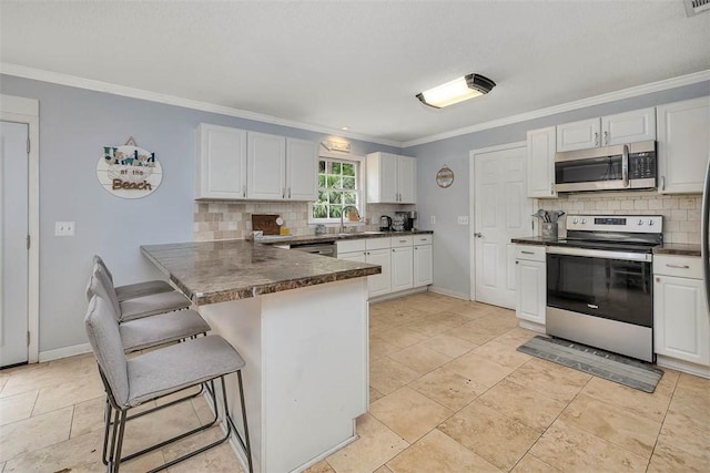 1201 Fairway Rd, Brunswick, GA 31525 - kitchen featuring stainless steel appliances, a kitchen bar, backsplash, a peninsula, and crown molding
