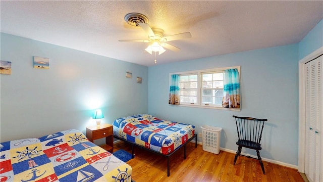 bedroom featuring wood finished floors, a closet, a ceiling fan, baseboards, and a textured ceiling