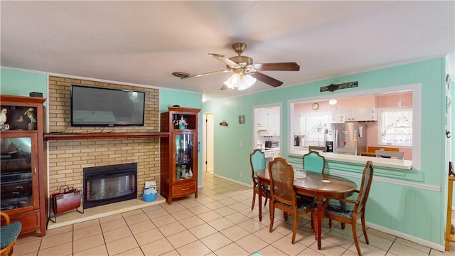 dining area with ceiling fan, a fireplace, light tile patterned floors, and crown molding