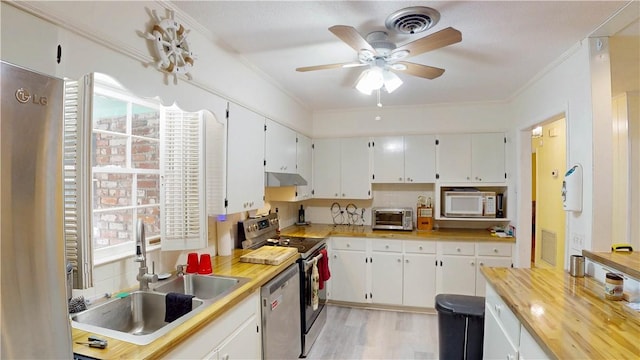kitchen featuring a sink, appliances with stainless steel finishes, a ceiling fan, white cabinetry, and light wood-style flooring