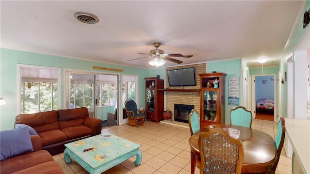 living area with attic access, a ceiling fan, light tile patterned flooring, a fireplace, and ornamental molding