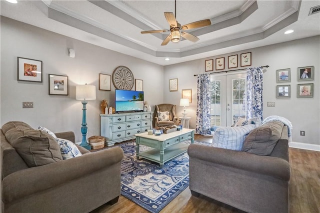 living room featuring a raised ceiling, dark wood-style floors, french doors, and ornamental molding