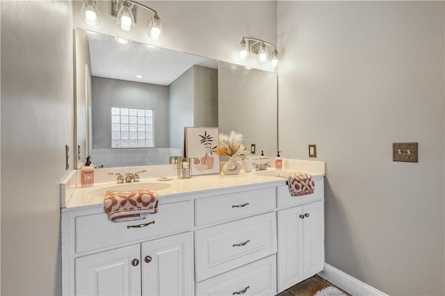 full bathroom with a sink, baseboards, and double vanity