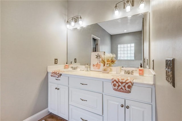 full bathroom with a sink, baseboards, and double vanity