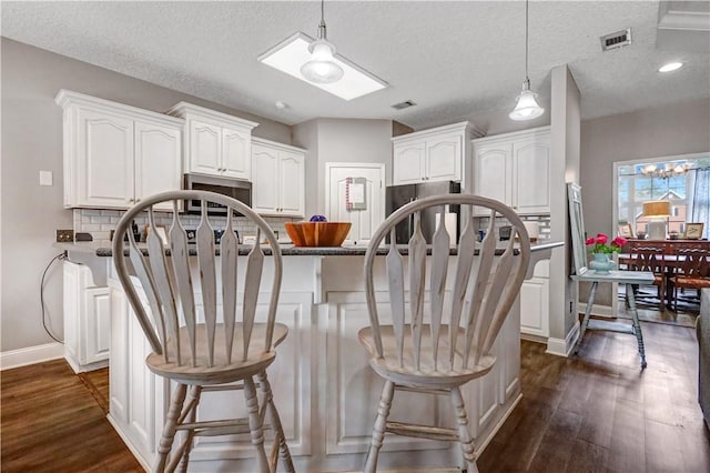 kitchen featuring white cabinetry, dark wood-style floors, visible vents, and stainless steel refrigerator