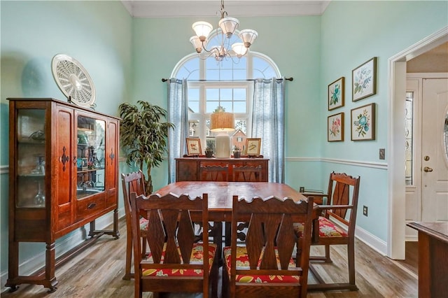 dining area with crown molding, a notable chandelier, wood finished floors, and baseboards