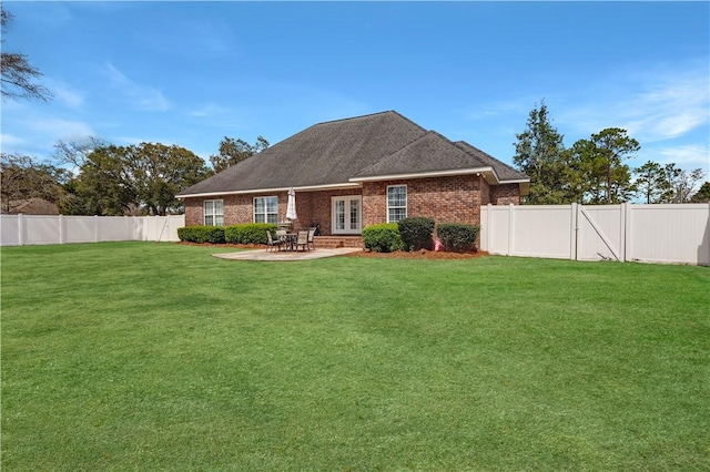 back of house featuring a patio, a lawn, a fenced backyard, and brick siding