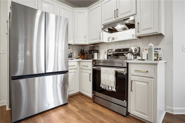 kitchen with stainless steel appliances, white cabinets, and light wood-type flooring