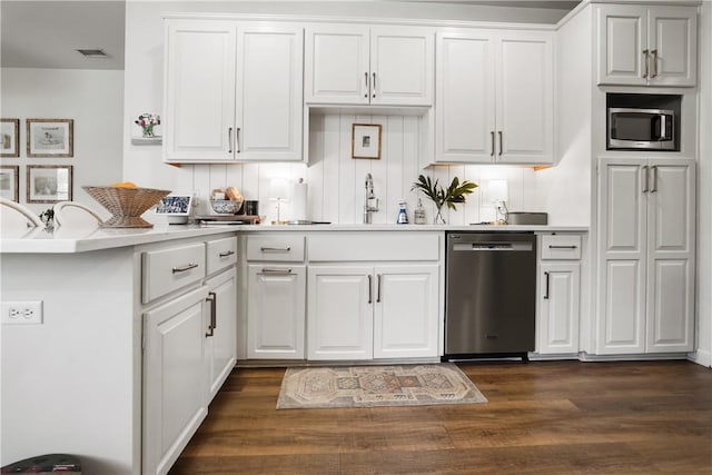 kitchen with tasteful backsplash, white cabinets, kitchen peninsula, stainless steel appliances, and dark wood-type flooring