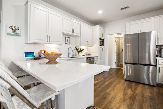 kitchen with a breakfast bar, stainless steel appliances, kitchen peninsula, and white cabinets