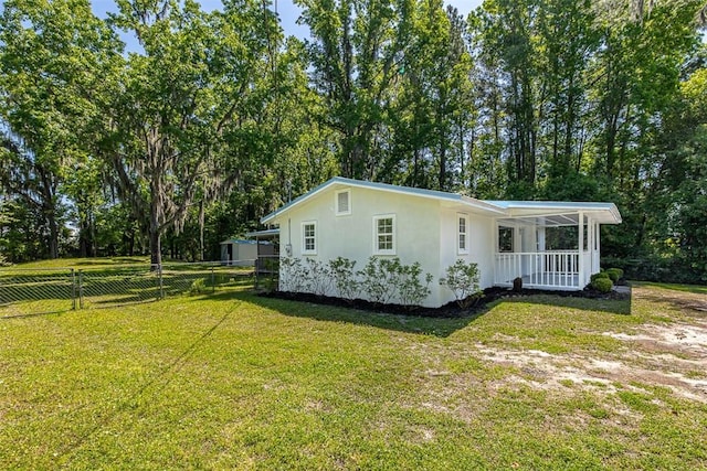 view of side of home featuring covered porch and a lawn