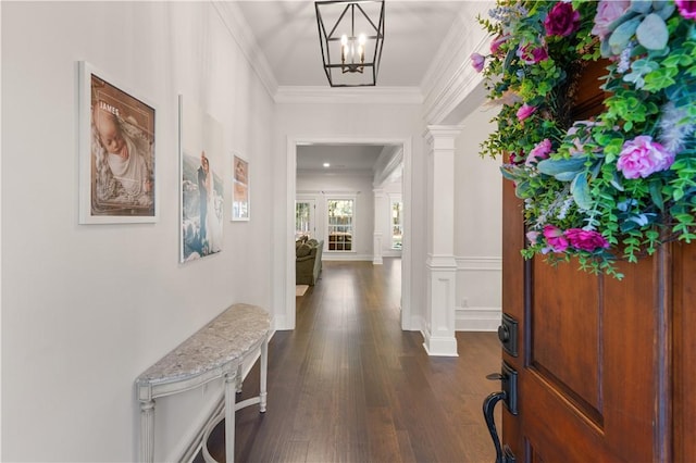 entrance foyer with crown molding, dark wood-type flooring, a chandelier, and ornate columns