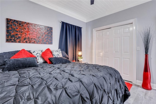 bedroom with a closet, light hardwood / wood-style floors, and ornamental molding