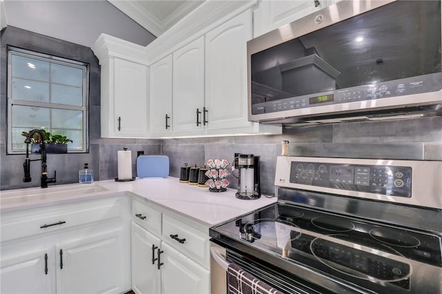 kitchen featuring white cabinetry, sink, stainless steel appliances, tasteful backsplash, and ornamental molding