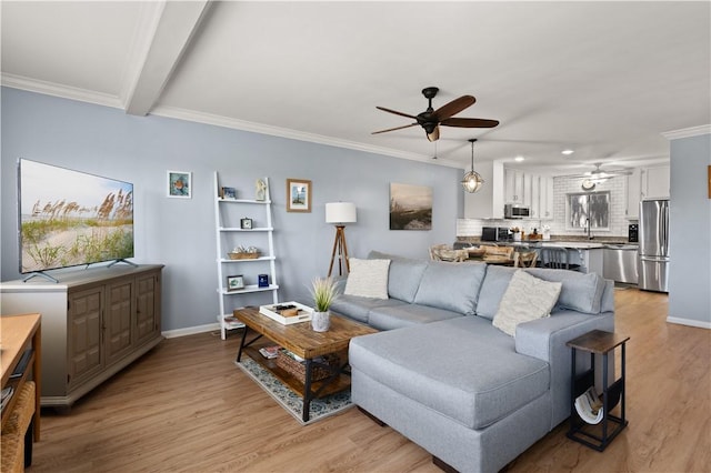 living room featuring ceiling fan, sink, light wood-type flooring, and ornamental molding